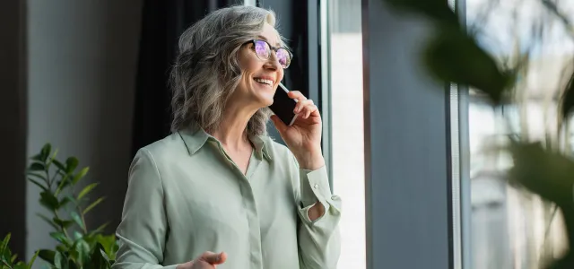 Happy mature woman talking on phone looking up